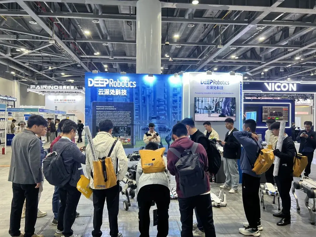 DEEP Robotics booth at IROS 2025 showcasing advanced quadruped robots, with visitors exploring the latest robotic innovations and autonomous walking systems.