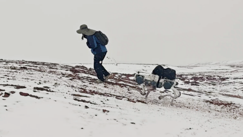 DEEP Robotics X30 Pro quadruped robot carrying supplies while walking alongside mountain patrol personnel in the Hoh Xil region.